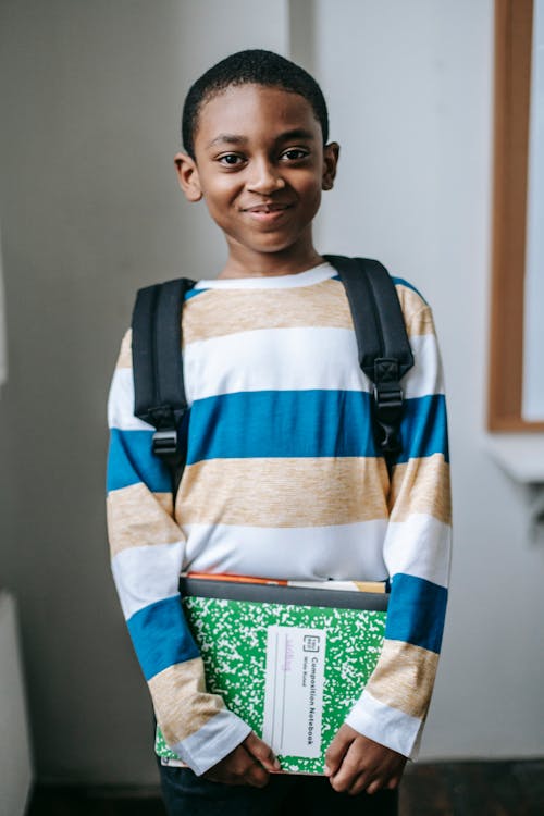 Free Smiling black child standing in classroom and looking at camera Stock Photo