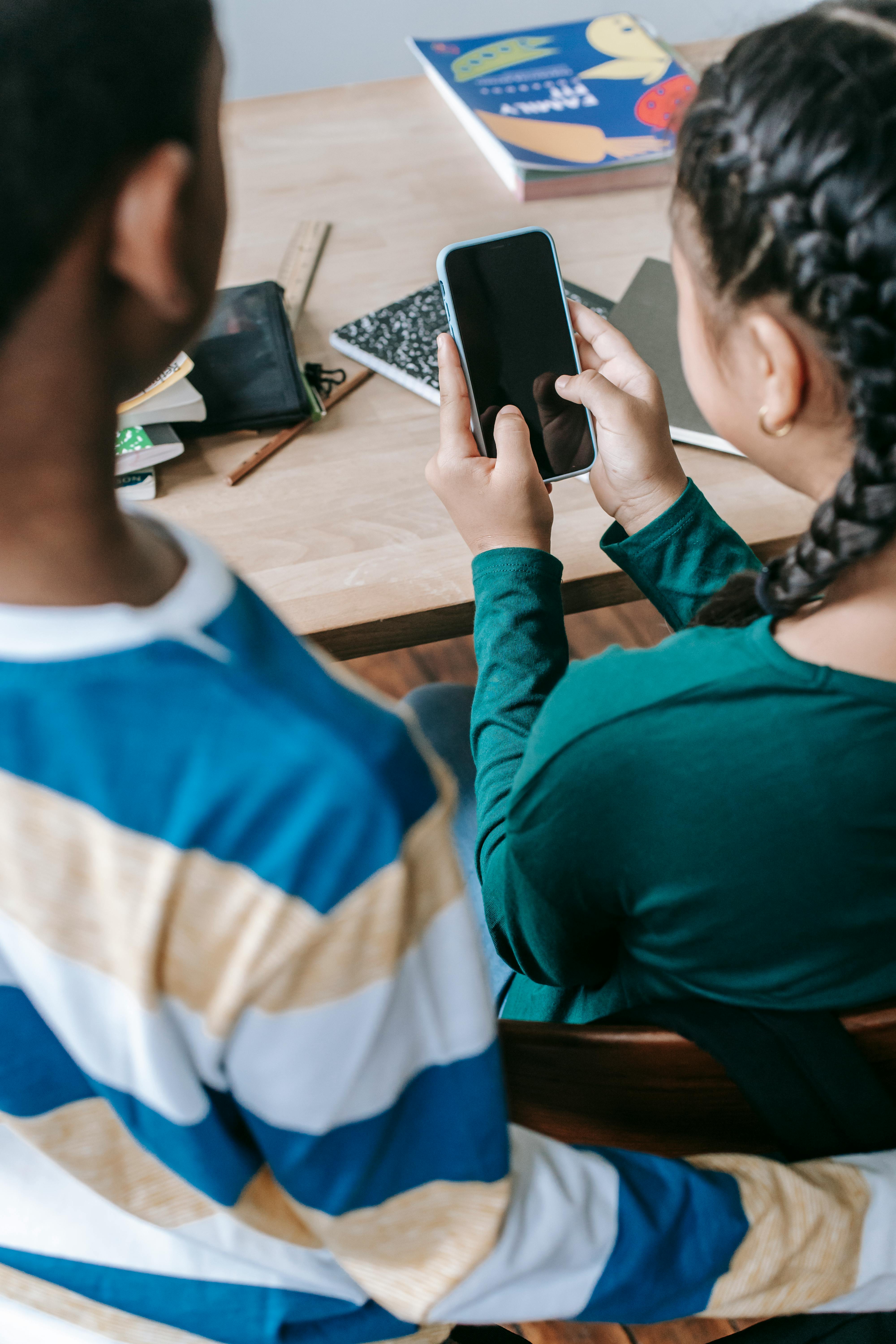 anonymous multiracial classmates browsing mobile phone at school