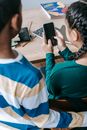 Anonymous multiracial classmates browsing mobile phone at school