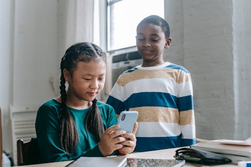 Multiethnische Kleine Schüler, Die Video Auf Smartphone Im Klassenzimmer Ansehen