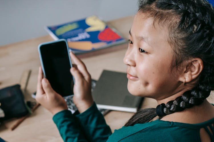 Joyful Ethnic Child Using Mobile Phone At School