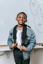 Cheerful black kid standing near whiteboard in classroom