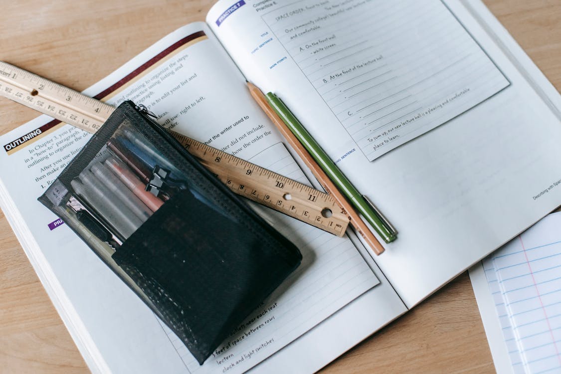 Textbook with pens and ruler on table