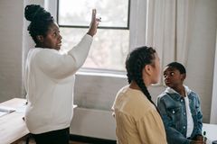 Clever African American woman explaining subject to attentive diverse pupils in modern classroom