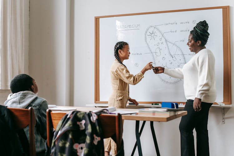 Black Woman Giving Marker To Asian Teen Girl