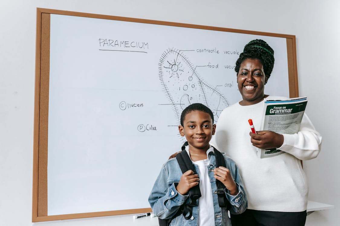 Cheerful Black woman with student against whiteboard