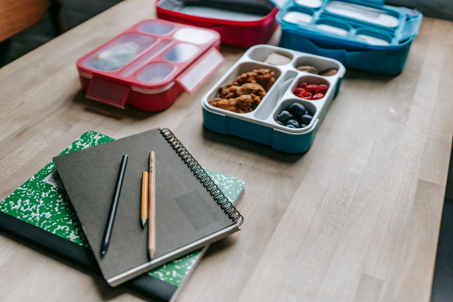 Lunch boxes behind notebooks on table