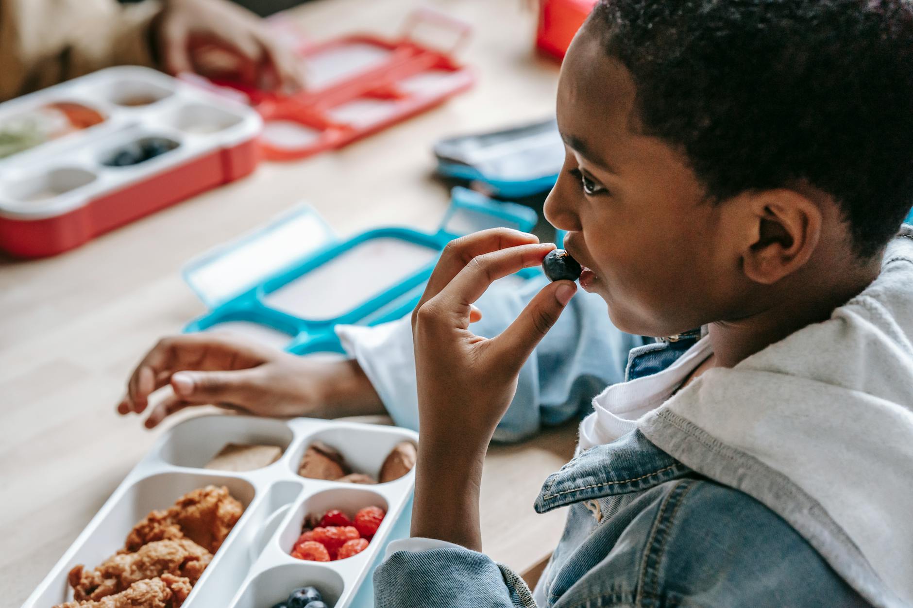 Young boy enjoying a healthy lunch with blueberries indoors.