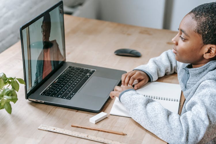 Crop Interested Black Schoolboy Listening To Teacher On Laptop Screen