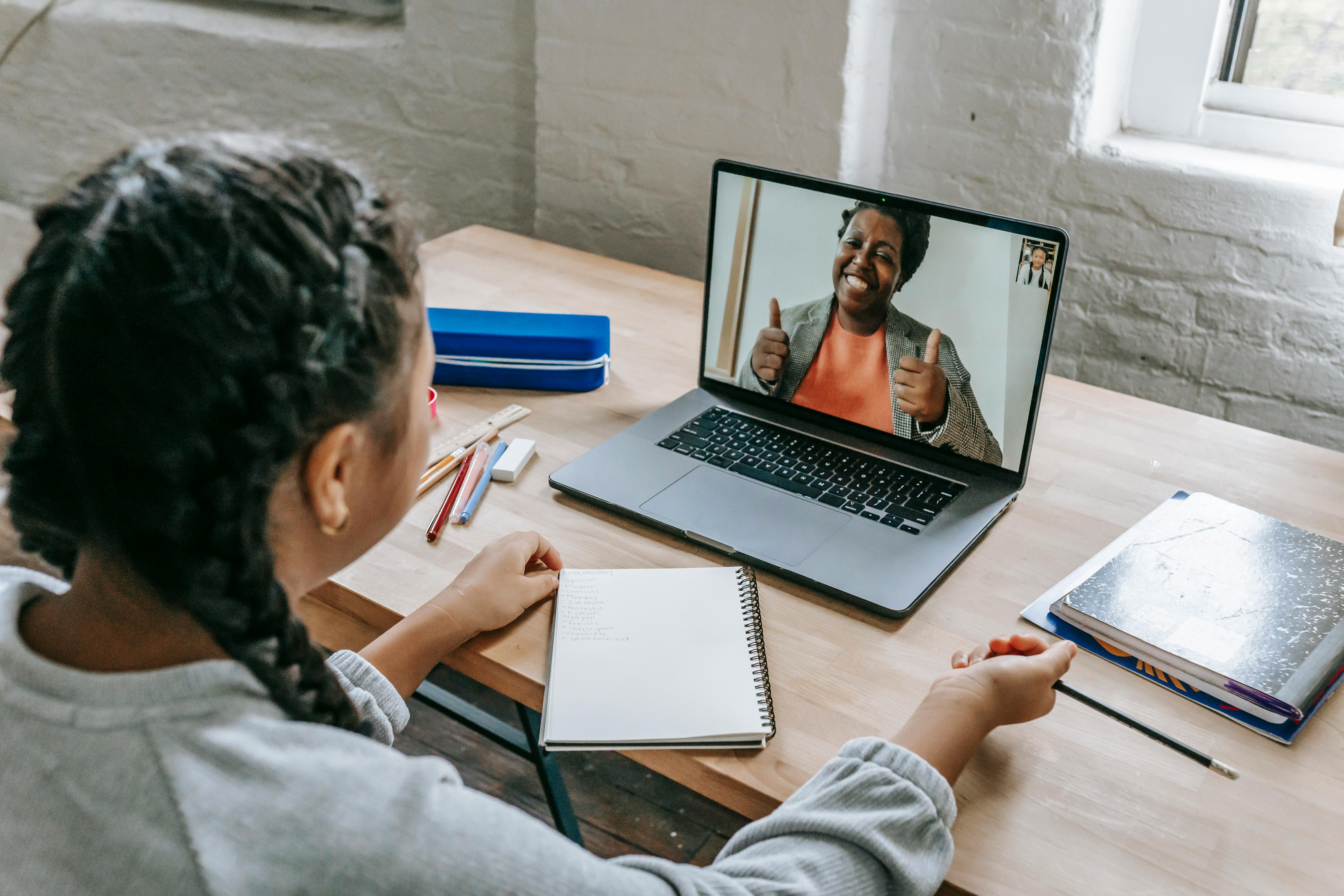 ethnic girl having video chat with teacher online on laptop