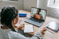 Ethnic girl having video chat with teacher online on laptop