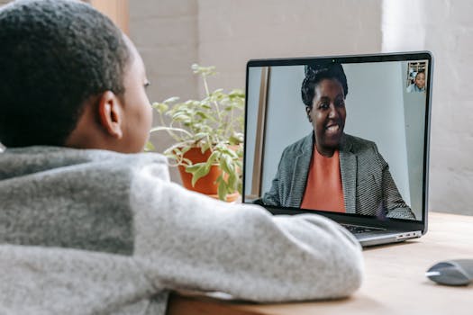 A young boy participates in online learning through a video call on his laptop.