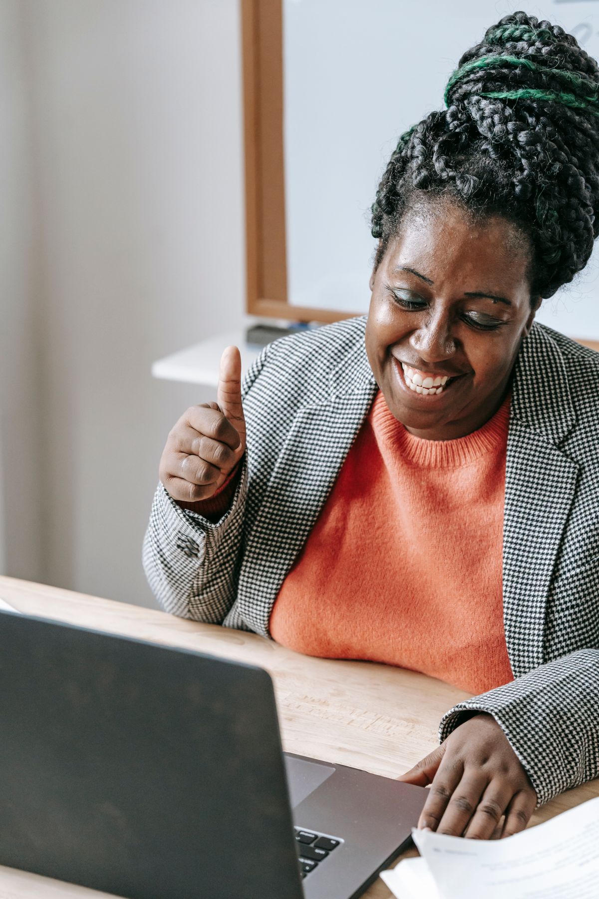 Smiling Black woman giving a thumbs-up during a telehealth video visit on her laptop