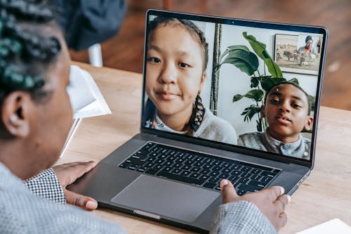 Free Black woman working online with pupils on laptop Stock Photo
