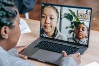 Black woman working online with pupils on laptop