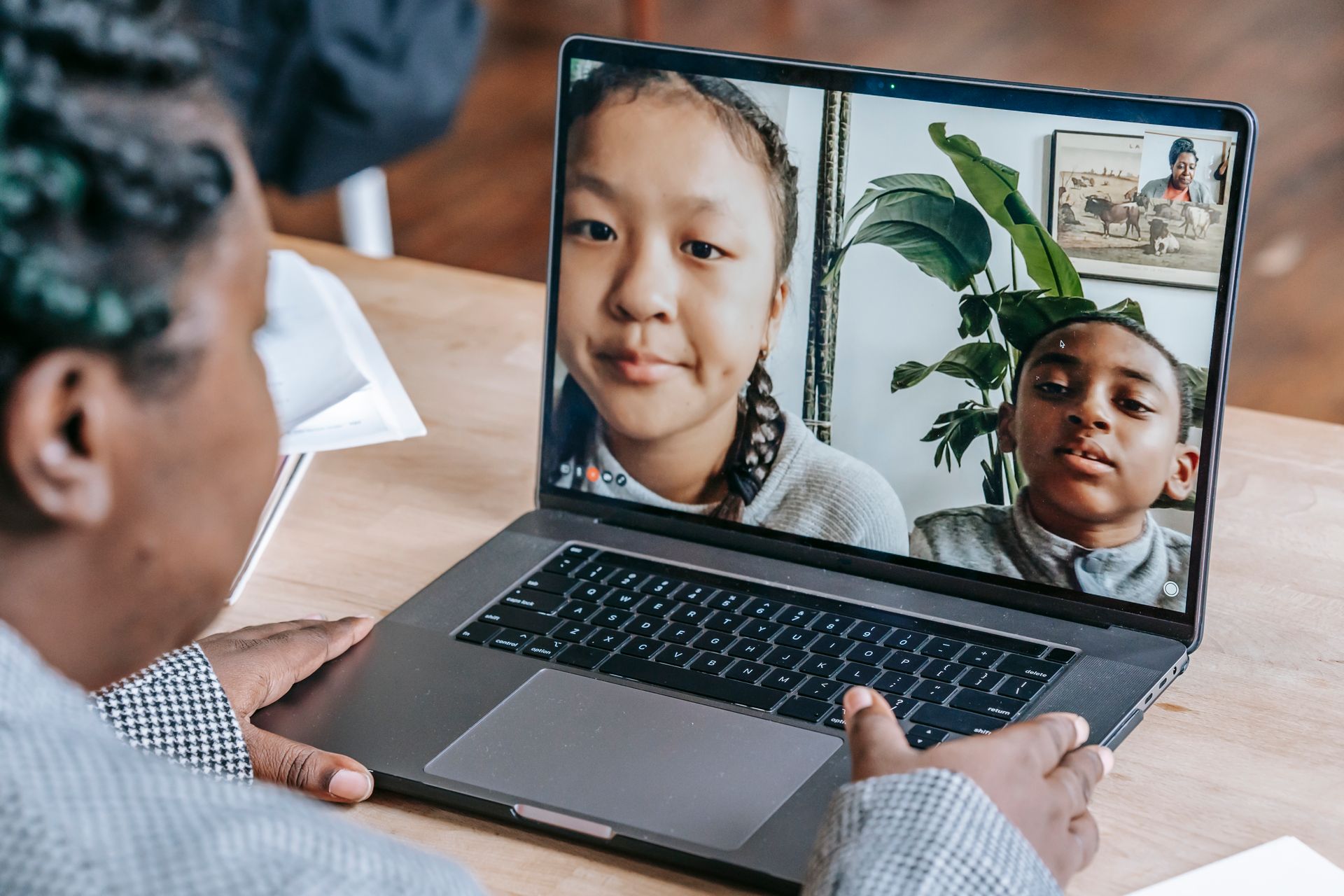 A teacher holding an online class with diverse students through a laptop during a distance learning session.