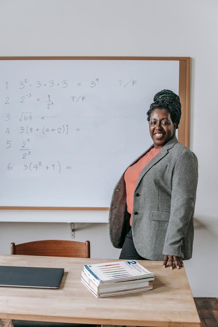 Proud Happy Black Teacher Near Whiteboard In Classroom