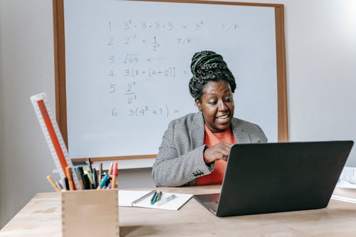 Amazed African American female giving lecture in mathematics online on netbook in classroom