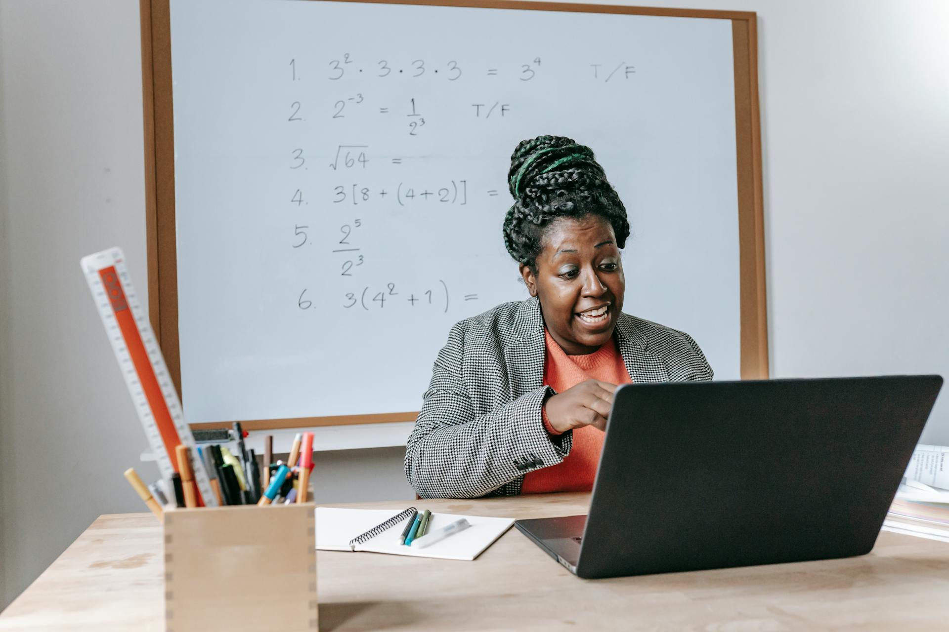 Amazed African American female giving lecture in mathematics online on netbook in classroom