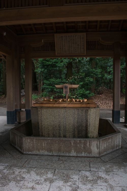 Free A serene scene of a water purification well at a traditional Japanese shrine amidst lush greenery. Stock Photo