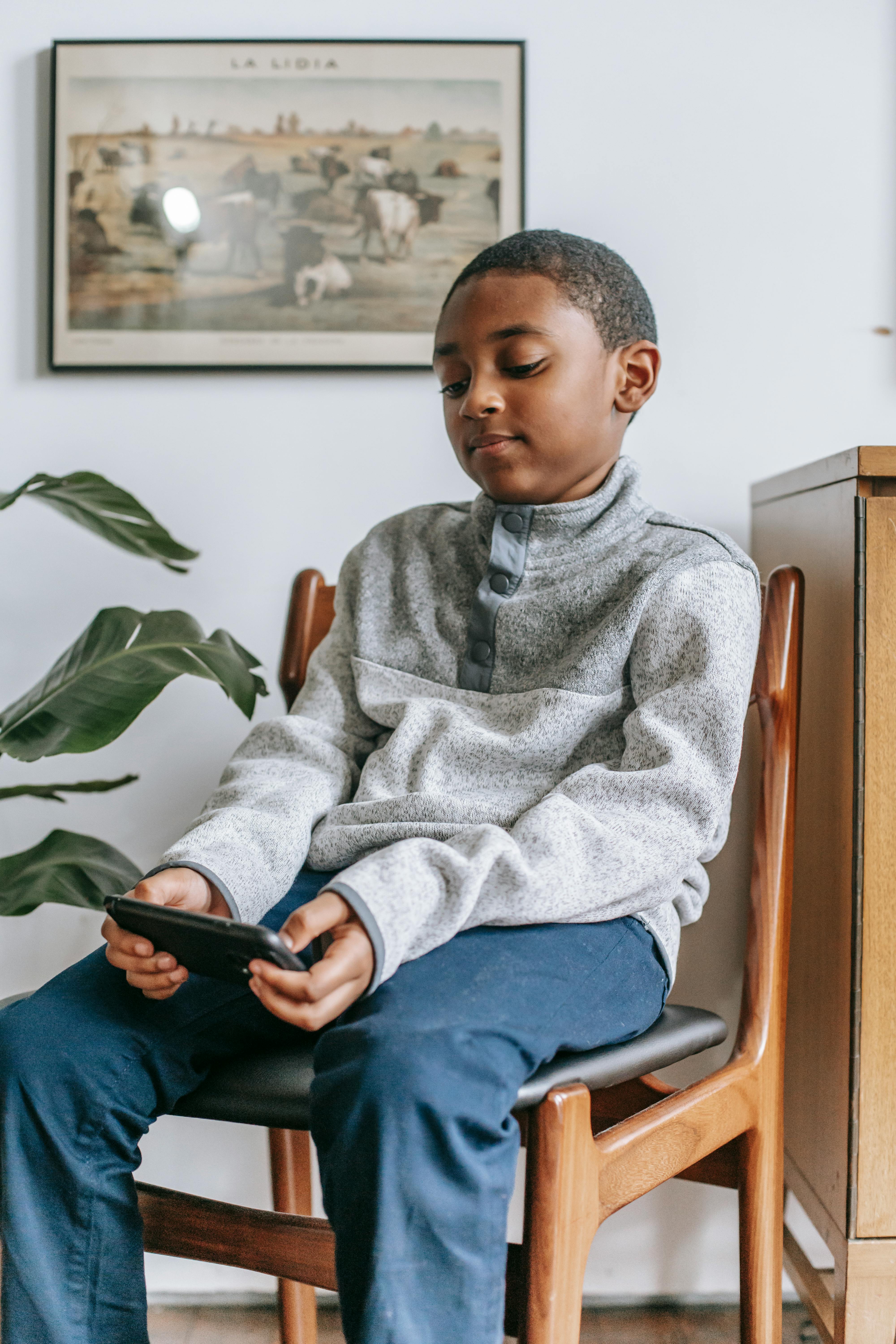 focused black boy with smartphone