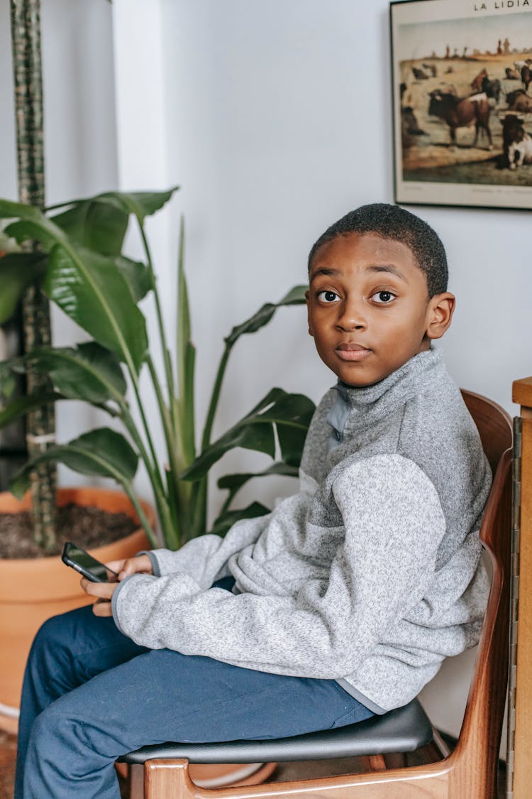 Black Boy On Chair With Smartphone