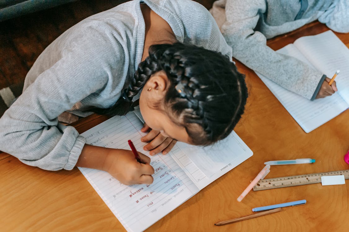 Free Children writing in copybooks at table Stock Photo