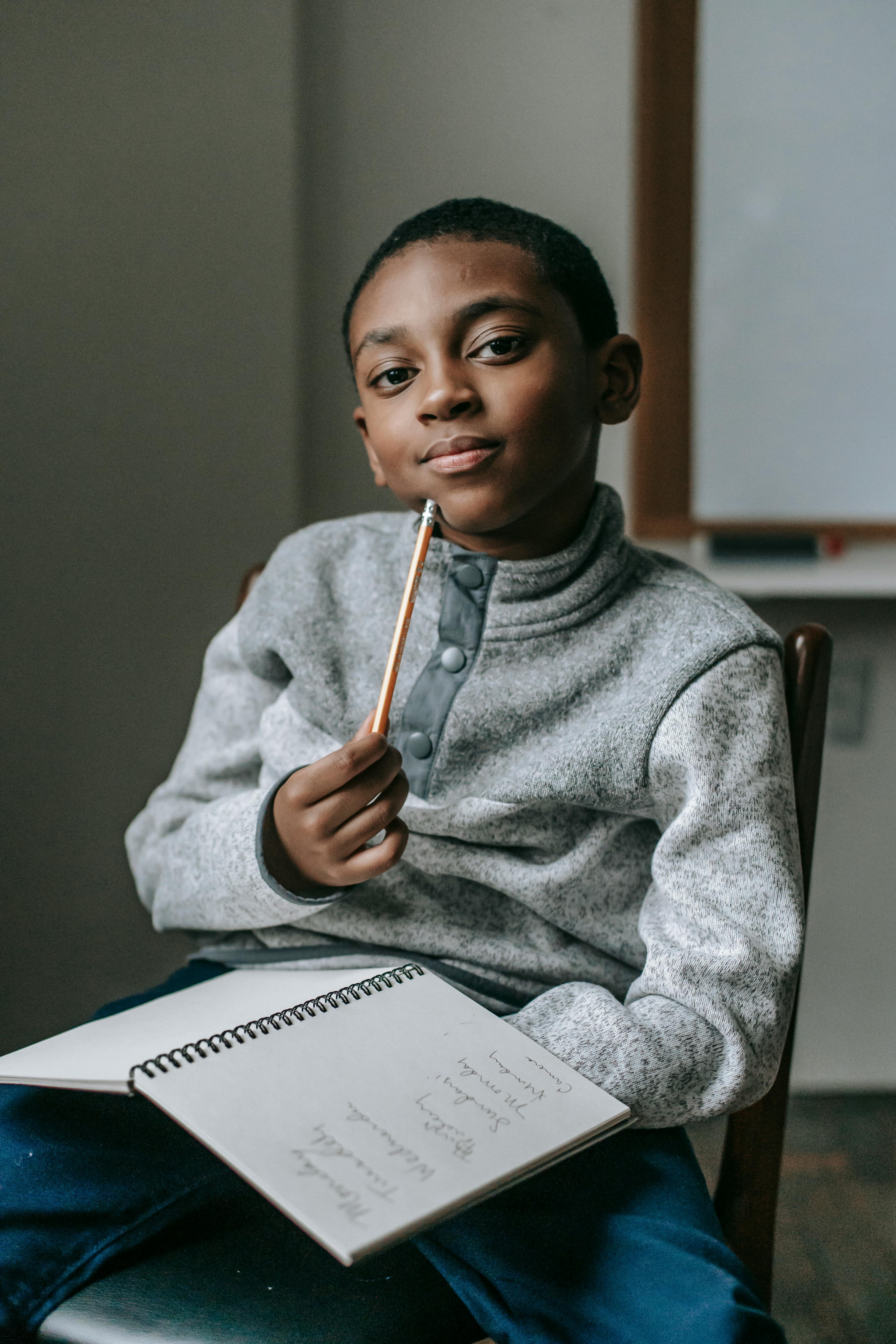 serious ethnic kid with pencil and copybook