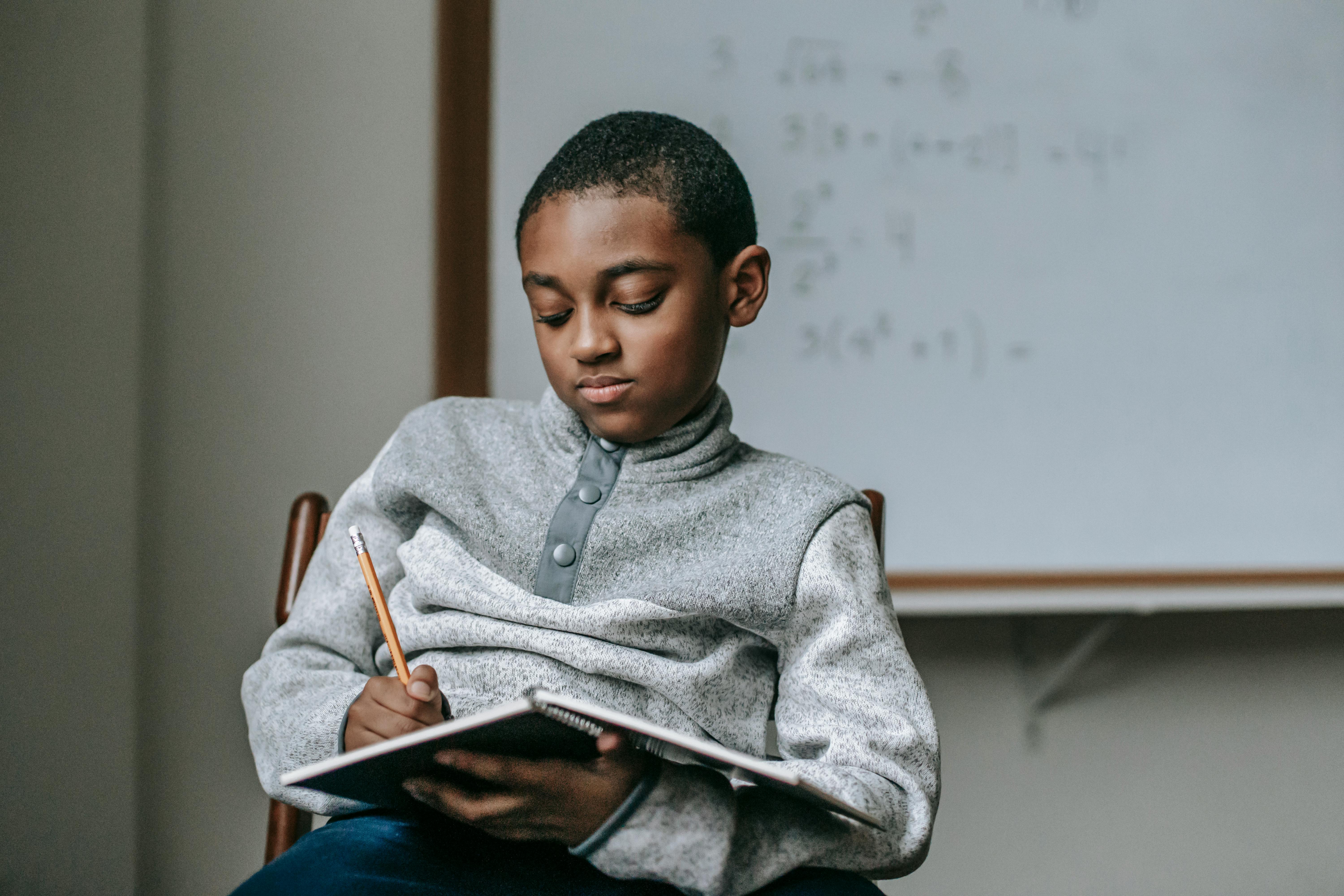 pensive ethnic kid doing task in copybook