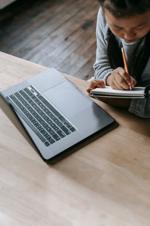 Crop student with laptop and notebook