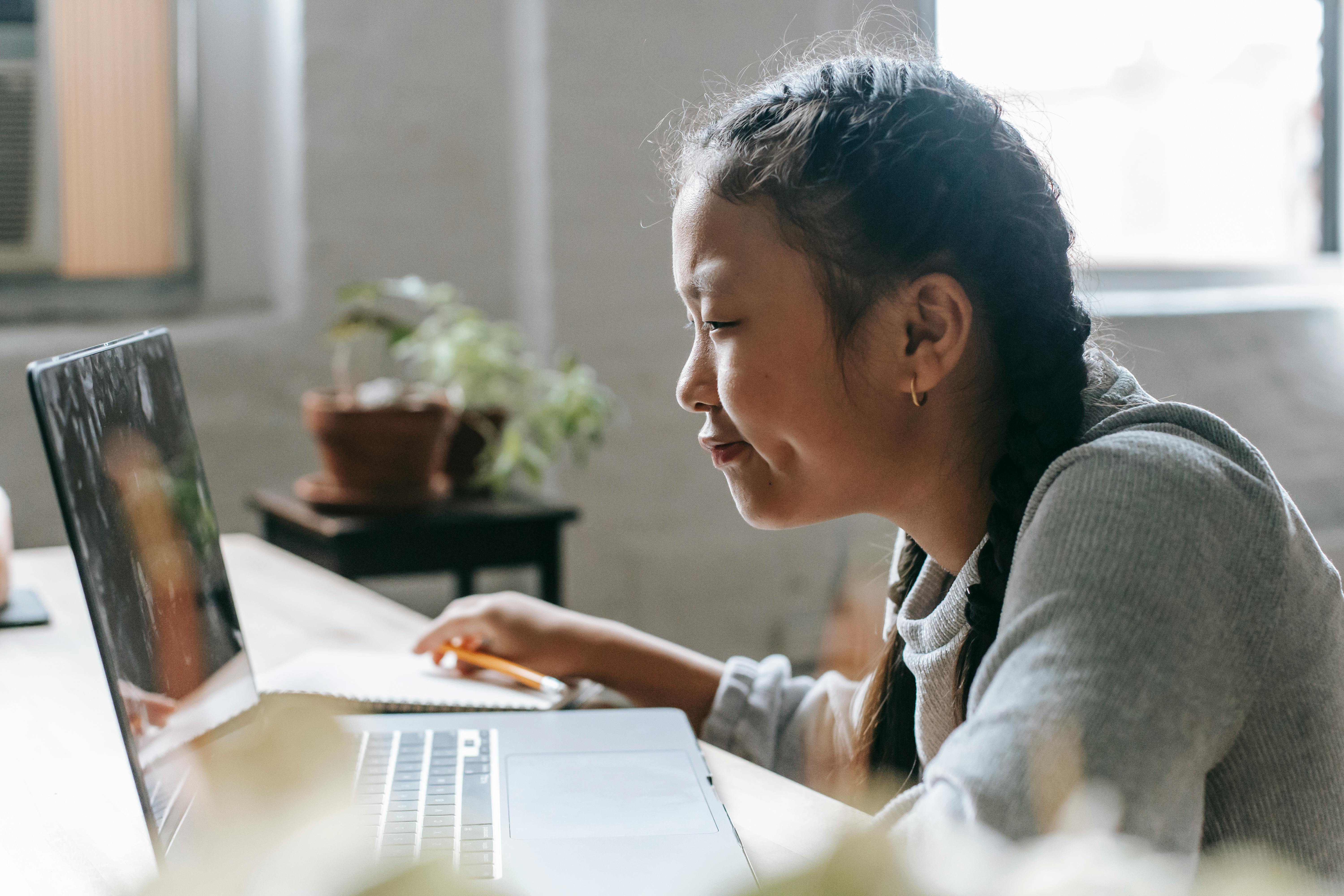 focused ethnic girl studying on laptop