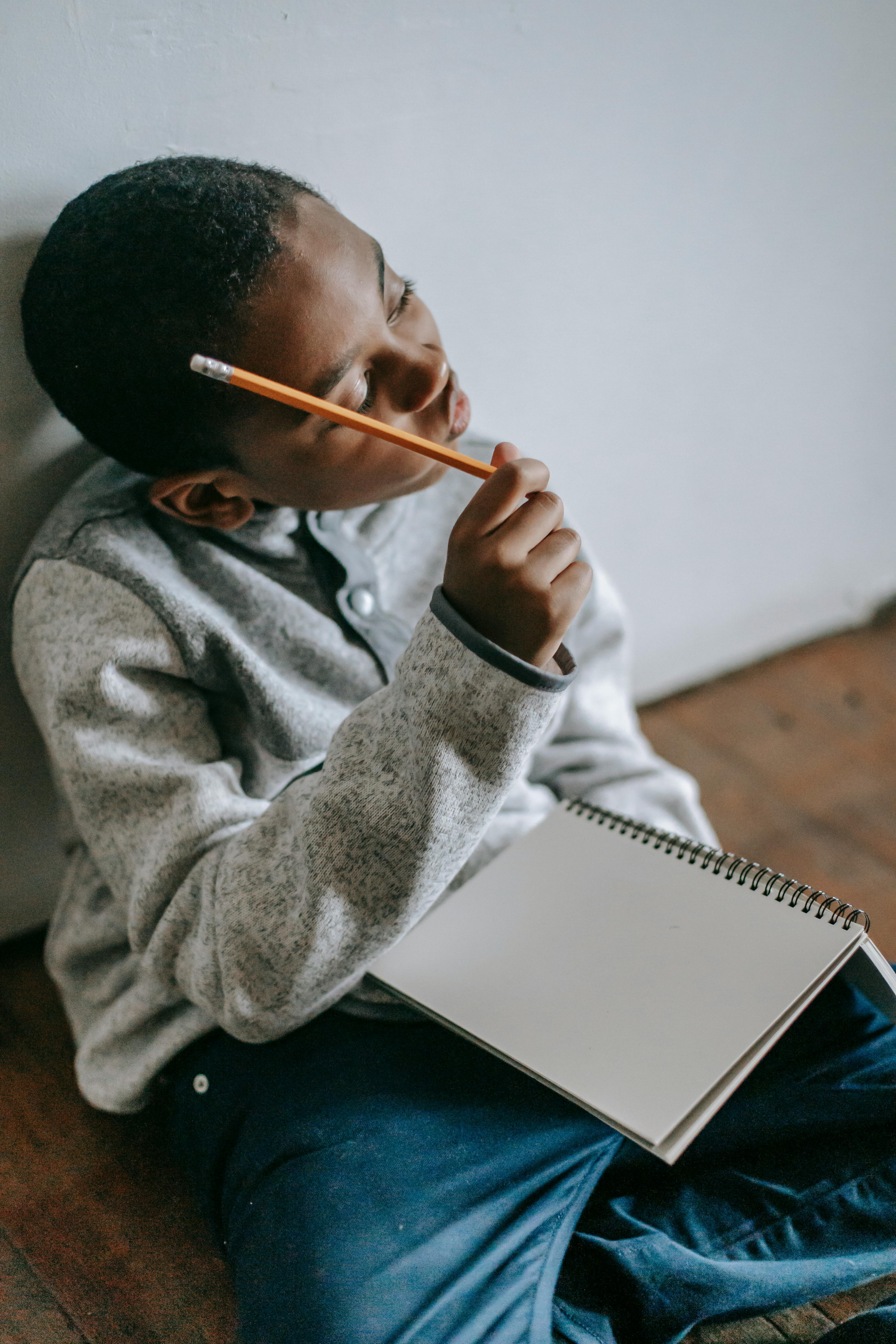 pensive black kid with notepad and pencil