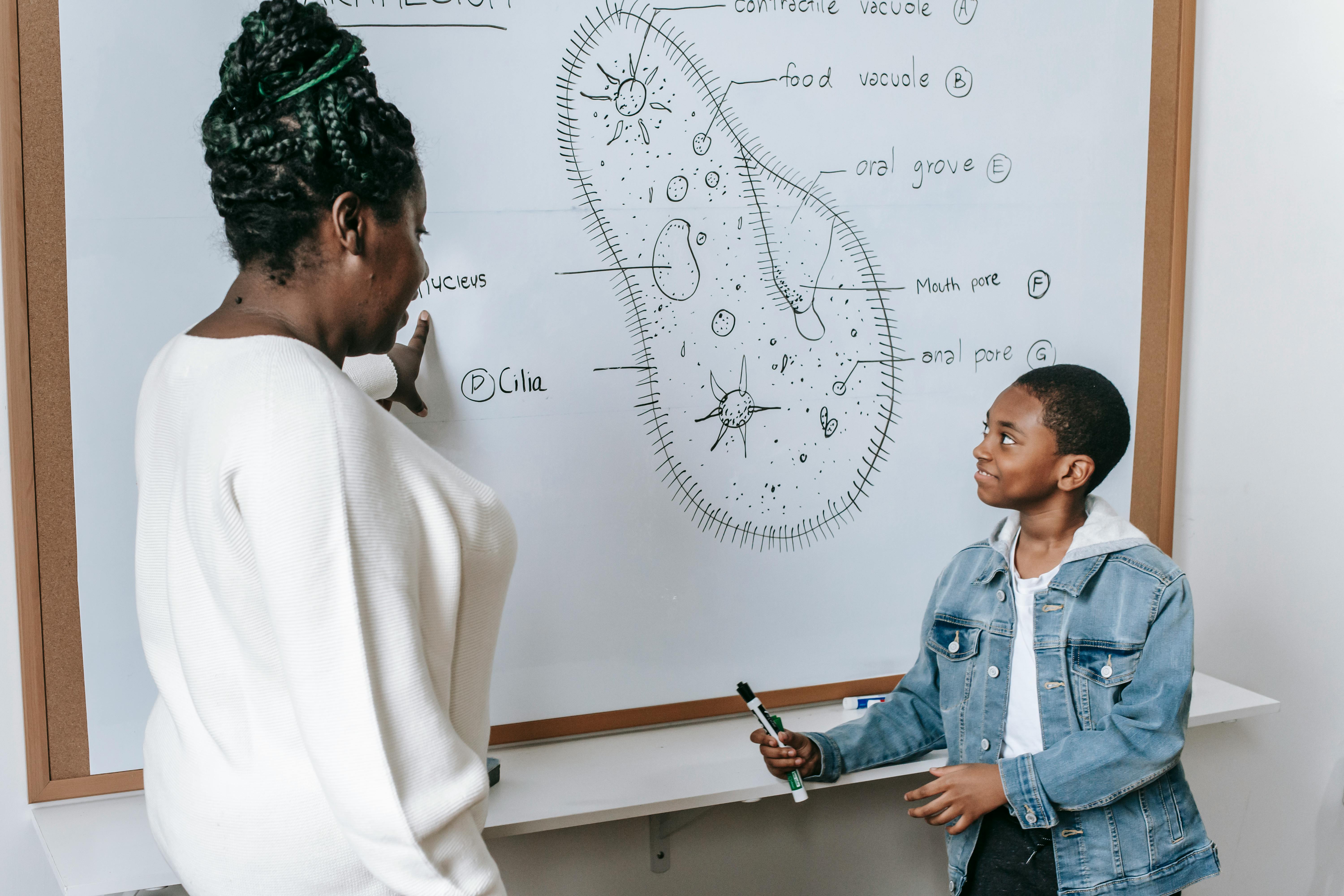 black teacher with boy at whiteboard