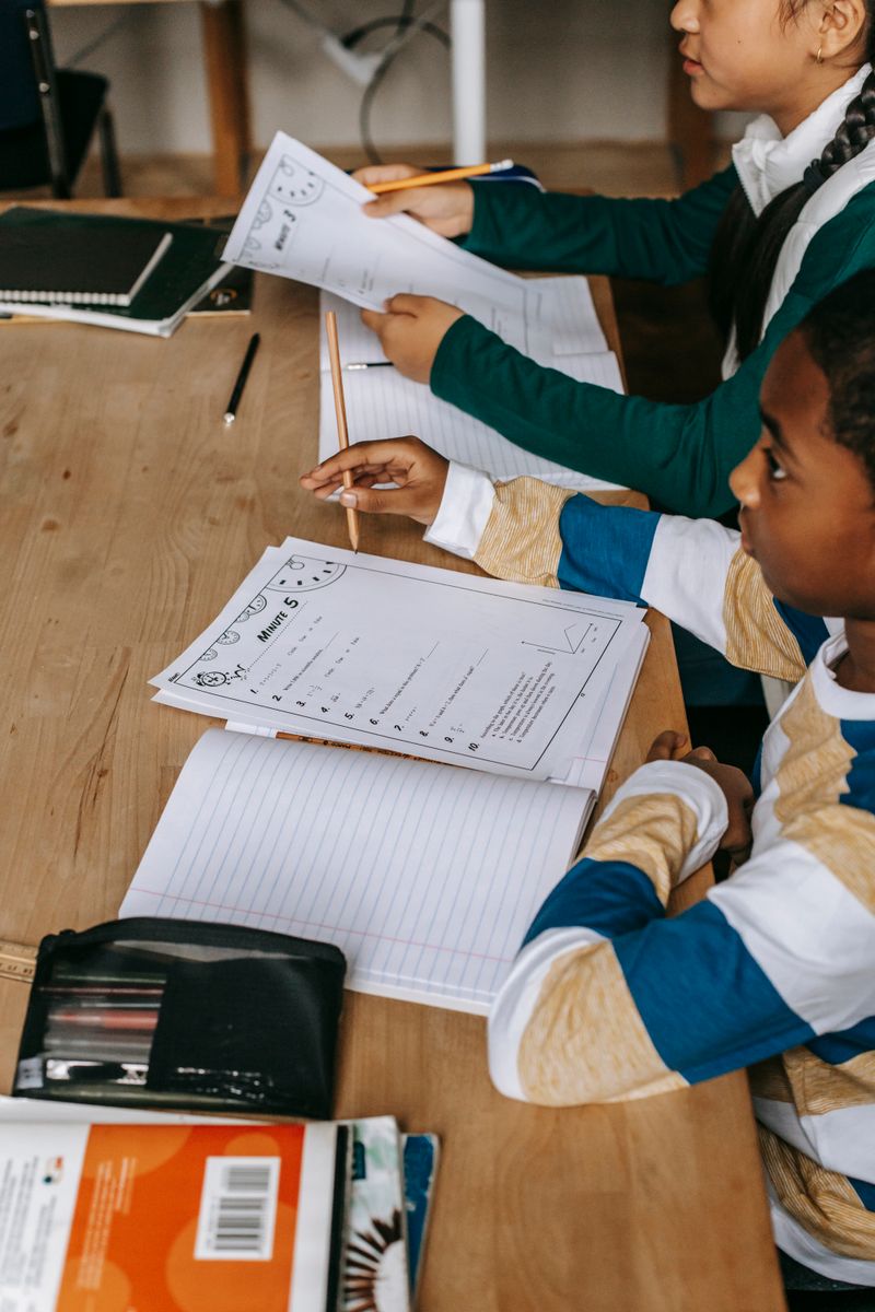 Side view of multiethnic smart boy and girl with notepads at wooden desk in classroom