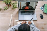 Black teacher on laptop screen during lesson with crop schoolboy