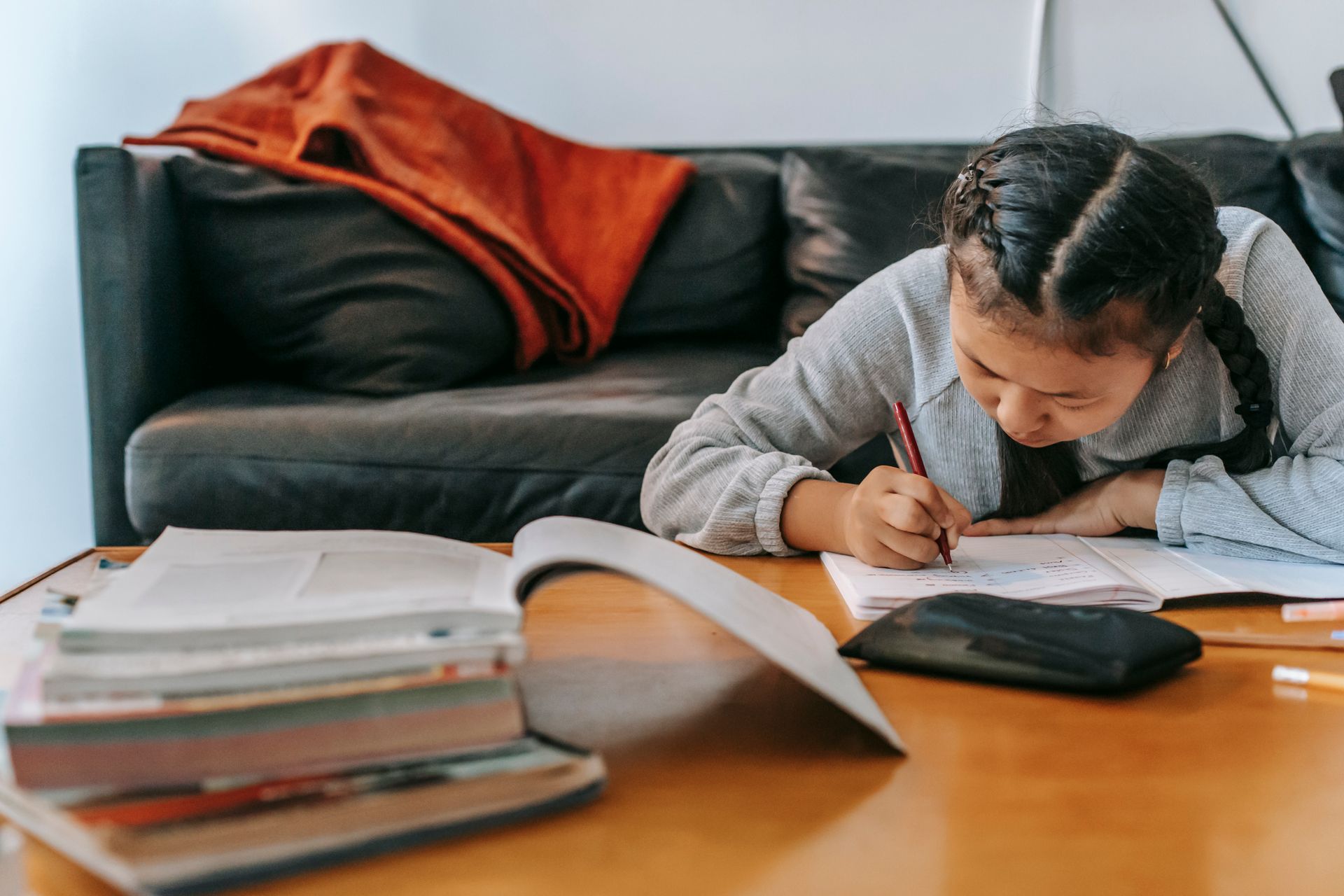 A child writing in a notebook at a coffee table