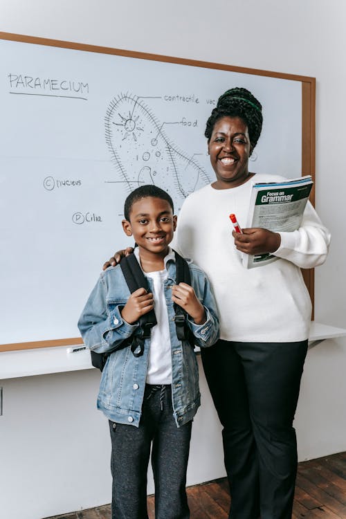 Happy black woman with pupil in classroom