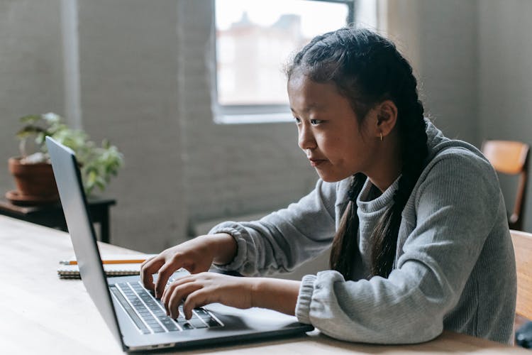 Focused Asian Girl Typing On Laptop At Home