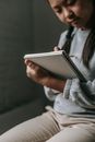 Crop serious Asian girl with pigtails wearing casual clothes sitting and preparing homework for school in copybook on blurred background