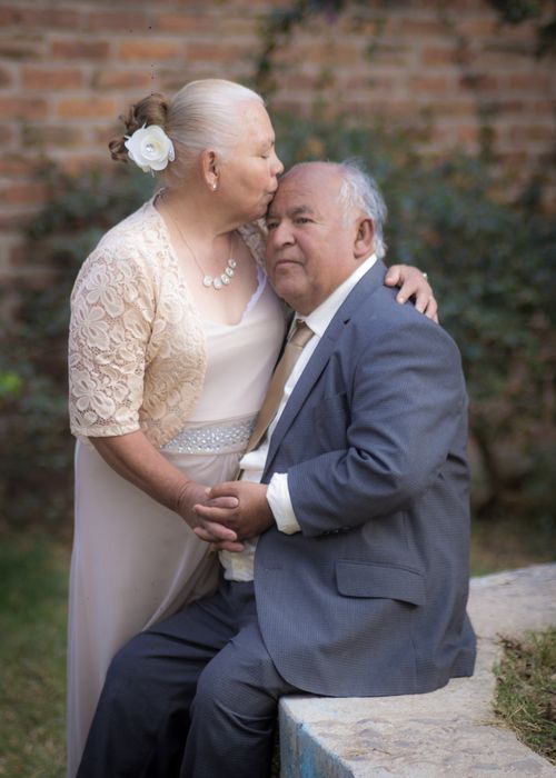 Free Elderly couple in formal attire sharing a tender kiss outdoors, symbolizing love and companionship. Stock Photo
