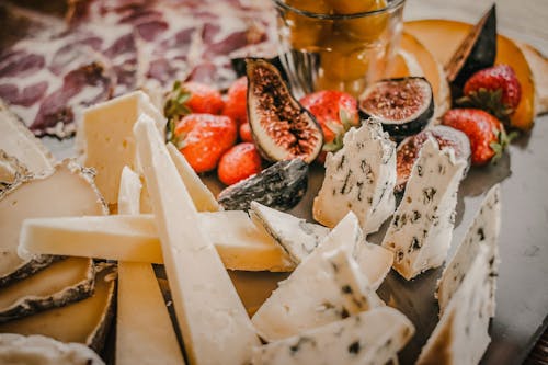 Various types of cheese near fruits and berries