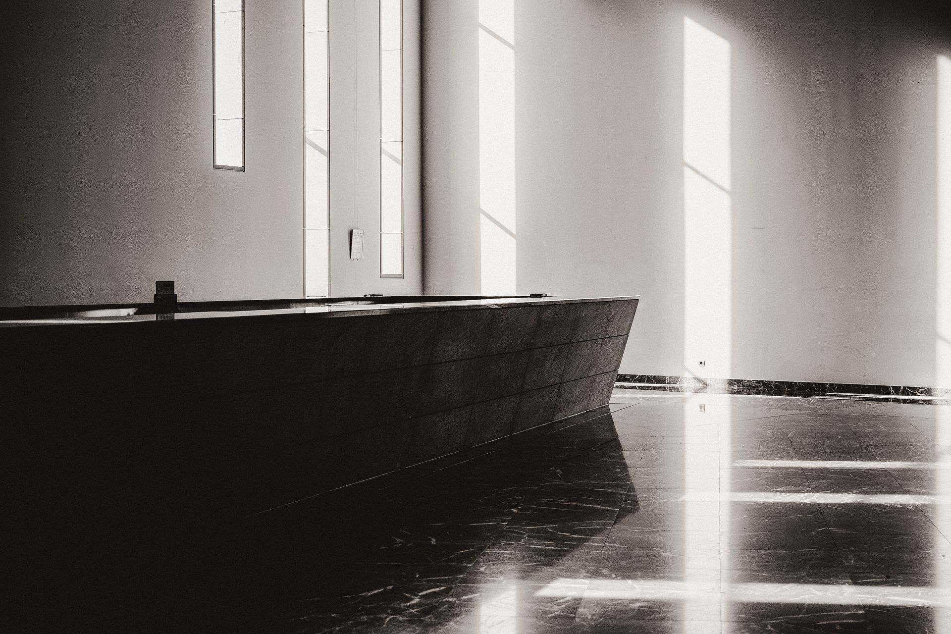 Interior of modern spacious bathroom with bath on tile floor next to windows
