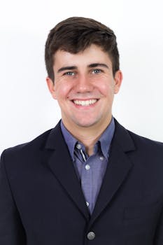 Smiling adult man in a smart suit against a white background.