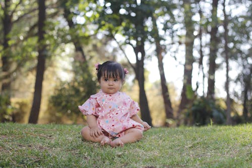 A Cute Girl in Pink Dress Sitting on the Grass