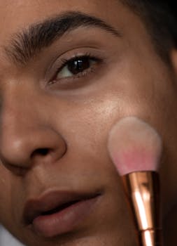 Detailed close-up of a person applying makeup with a brush highlighting smooth skin texture.