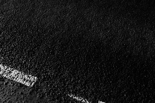 From above black and white of textured background representing asphalt roadway with marking lines