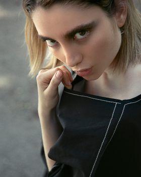 Stylish young woman in a black outfit poses outdoors, creating a bold fashion statement.