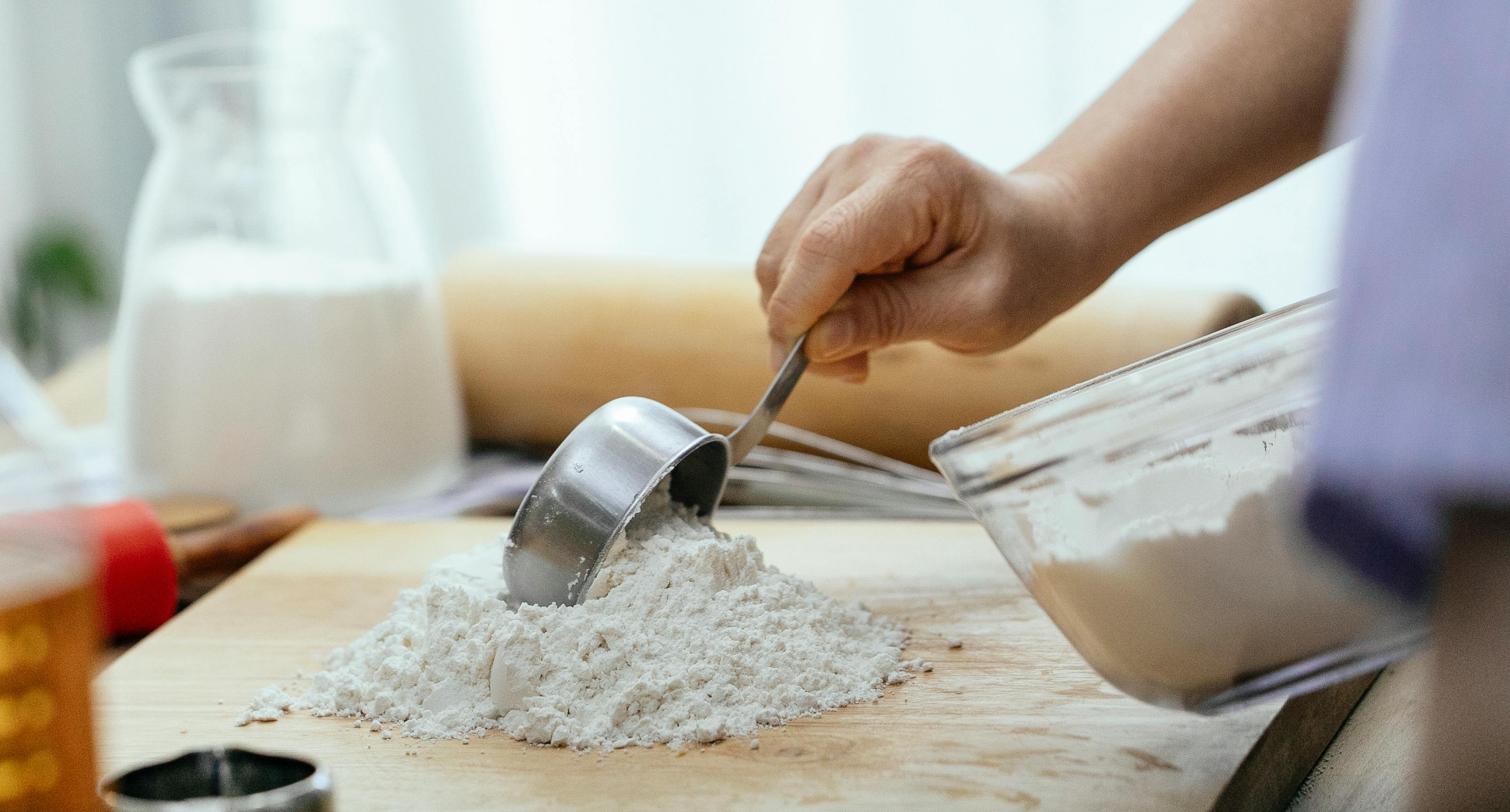 crop adult woman adding flour on wooden cutting board