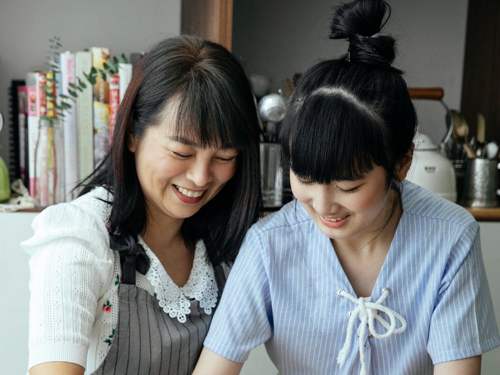 Asian mother standing with daughter on kitchen