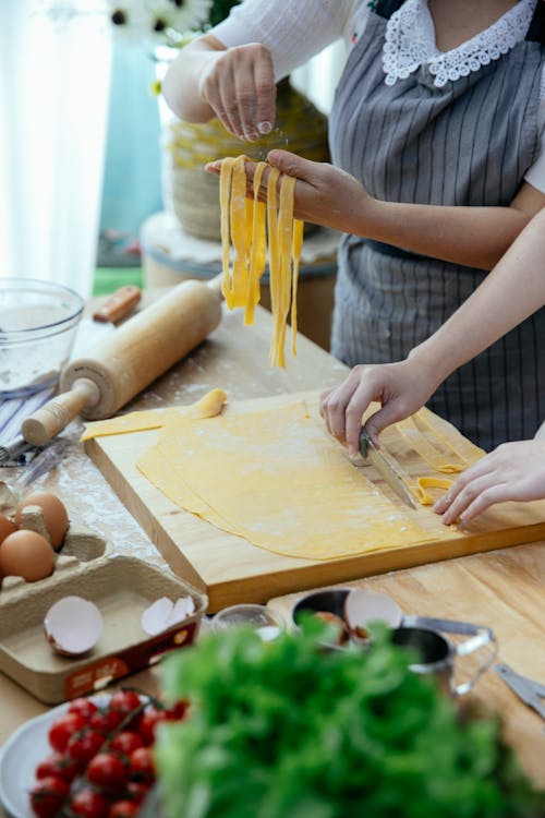 Free Women making hand pulled noodles in kitchen Stock Photo